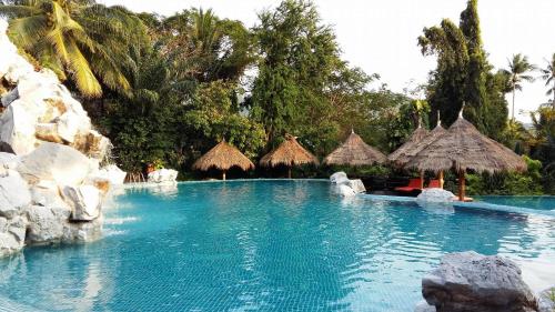 a swimming pool with umbrellas and chairs in a resort at Koh Tao Cabana in Koh Tao