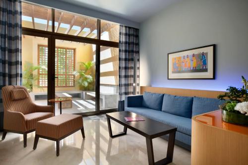 a living room with a blue couch and a table at Kempinski Hotel Ishtar Dead Sea in Sowayma