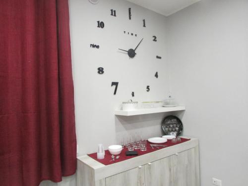a white wall with a clock and a red curtain at B&B da Lillo in Frosinone