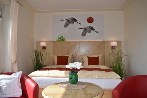 a bedroom with a bed and a vase of flowers on a table at Alago Hotel am See in Cambs