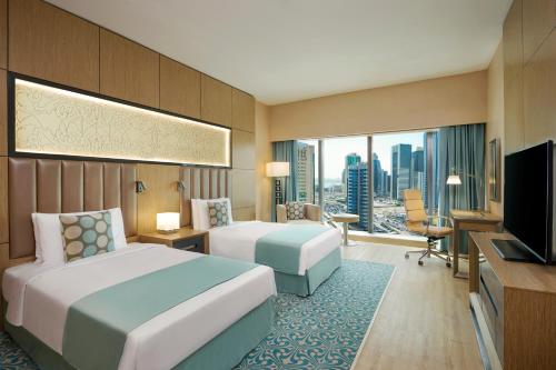a hotel room with two beds and a television at Wyndham Doha West Bay in Doha