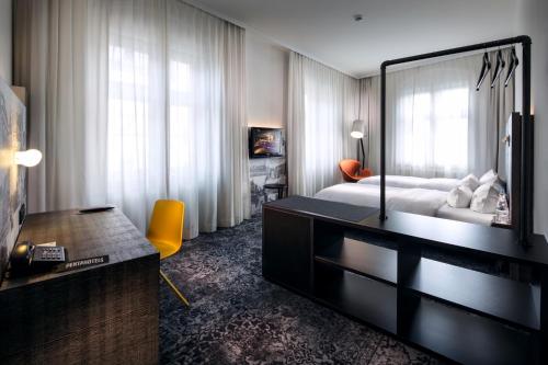 a bedroom with a bed and a desk with a mirror at pentahotel Braunschweig in Braunschweig