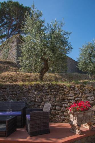 a stone wall with a table and chairs and flowers at La Magione dei Todaro in Borgo a Buggiano