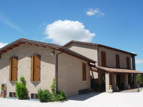 a house with brown shuttered windows and a blue sky at Colleverde Country House & SPA Urbino in Urbino