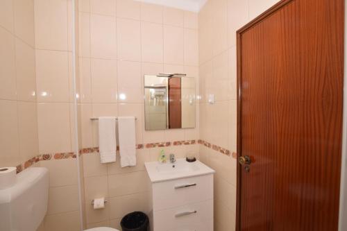 a bathroom with a sink and a toilet and a mirror at Apartamentos Carruna in Albufeira