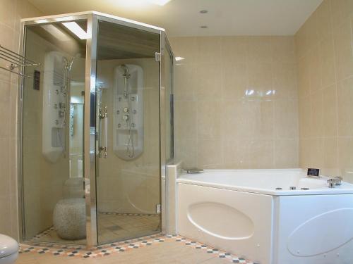 a bathroom with a shower and a white tub at Swan Lake Motel in Guishan