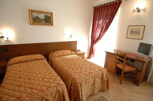 a hotel room with two beds and a desk at Colleverde Country House & SPA Urbino in Urbino