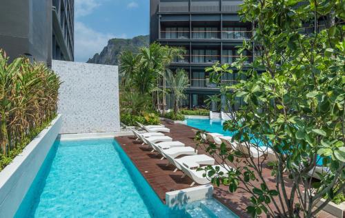 a pool with lounge chairs next to a building at Panan Krabi Resort in Ao Nang Beach