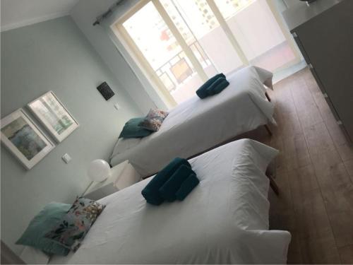 2 białe łóżka w pokoju z oknem w obiekcie Apartamento T&T Ocean no Clube Praia da Rocha. w mieście Portimão