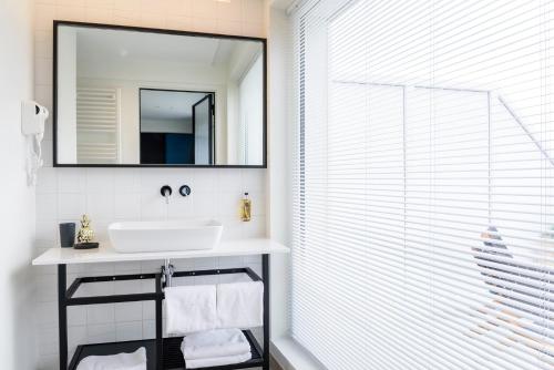 a bathroom with a sink and a mirror at Hotel Nelson in Knokke-Heist
