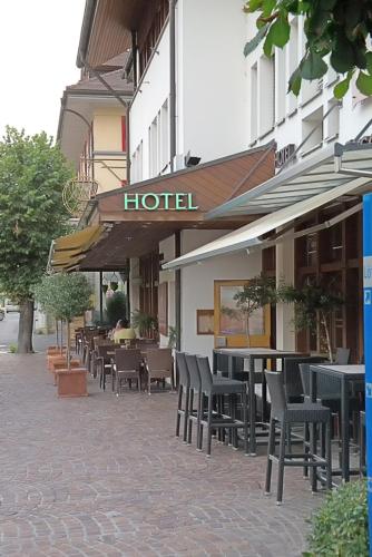 a hotel with tables and chairs on a sidewalk at Hotel Lötschberg in Spiez