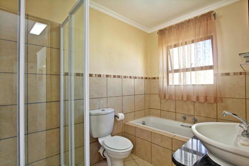 a bathroom with a toilet and a tub and a sink at Uvongo River Resort in Margate