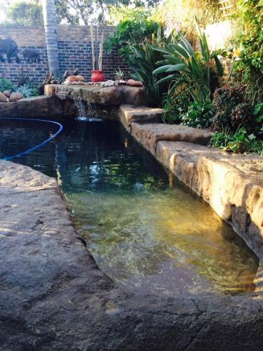 un estanque en un patio trasero con un camino de piedra en Sunninghill Sojourn, en Kyalami