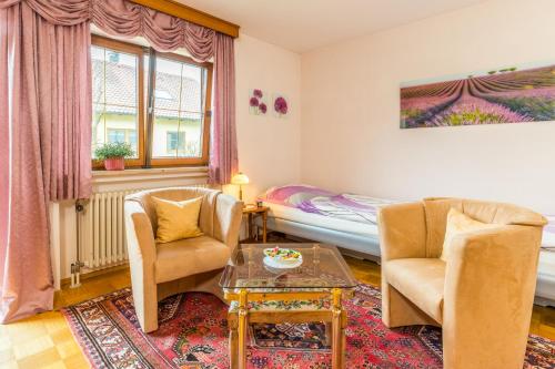 a living room with two chairs and a table and a bed at Privatzimmer Ulbricht/Föhr in Friedrichshafen