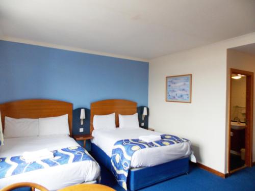 two beds in a room with blue walls at London - Wembley International Hotel in London