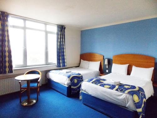 a hotel room with two beds and a table at London - Wembley International Hotel in London