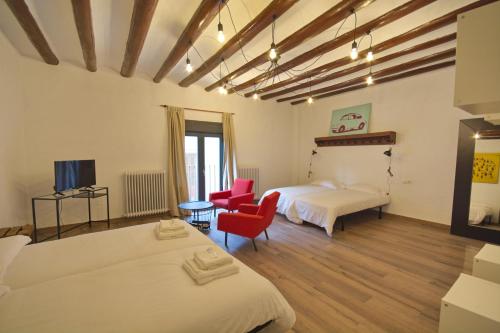1 dormitorio con 2 camas y silla roja en Pension Casa Pinilla en Cascante