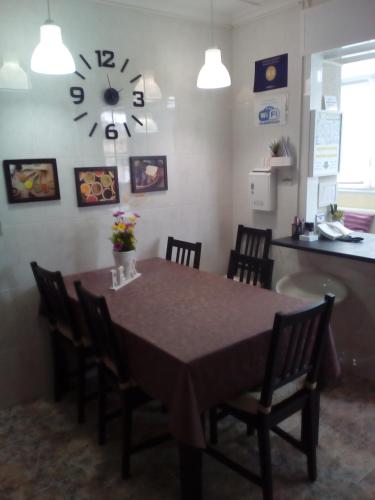 a dining room table with chairs and a clock on the wall at Albergue Aqua Portomarin in Portomarin