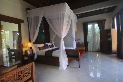 a bedroom with a bed with a canopy at Ubud Paradise Villa in Ubud