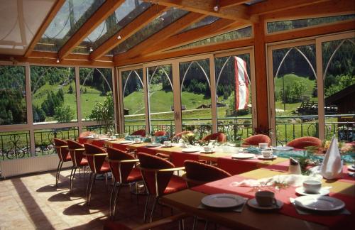 uma sala de jantar com mesas, cadeiras e janelas em Hotel-Gasthof Waldcafé em Neustift im Stubaital