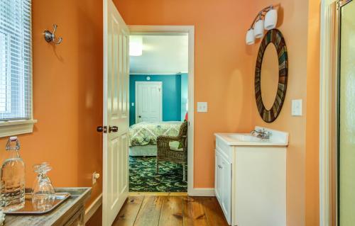 uma casa de banho com paredes cor-de-laranja, um lavatório e um espelho. em Twin Oaks Inn em Saugatuck