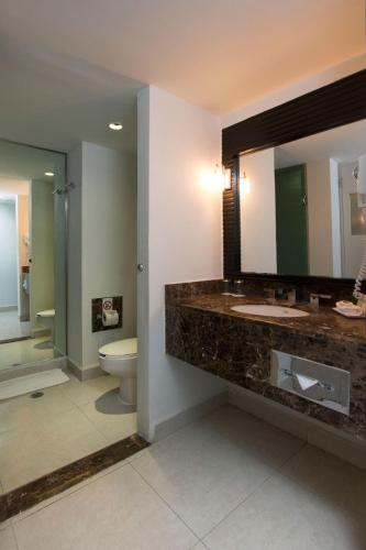 a bathroom with a sink and a toilet and a mirror at Grand Decameron Los Cabos, A Trademark All-Inclusive Resort in San José del Cabo