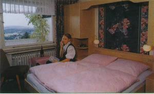 a woman sitting next to a bed in a bedroom at Hotel Im Hagen in Königswinter