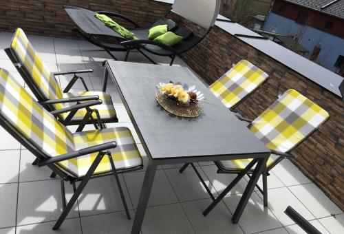 una mesa con sillas amarillas y negras en el patio en Apartmán Monika, en Lipno nad Vltavou