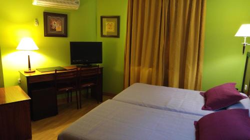 a bedroom with a bed and a desk with a television at Hotel Cabañas in Puertollano