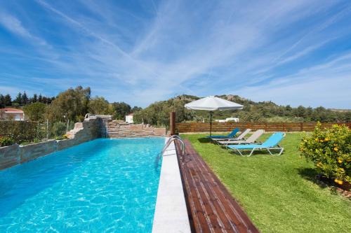 a swimming pool with two chairs and an umbrella at Natura House in Ialyssos