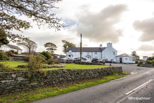 a white building with a stone wall next to a street at Lastra Farm Hotel in Amlwch
