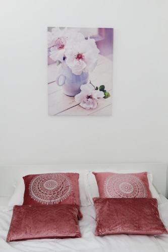 a bed with two red pillows and a vase with flowers at Apartment Dina, Self check in 0-24 in Karlovac