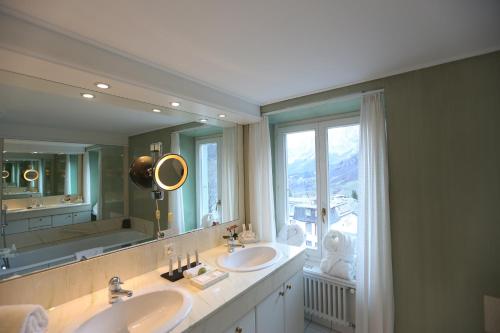 un bagno con due lavandini e un grande specchio di Résidence Les Sources des Alpes a Leukerbad