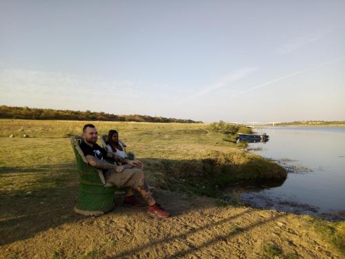 a man and a woman sitting on a chair next to a lake at Ranthambhore Tiger Valley in Sawāi Mādhopur