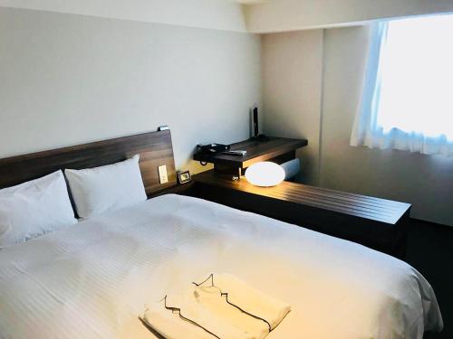 a bedroom with a bed with a desk and a window at BRENZA HOTEL in Kobe