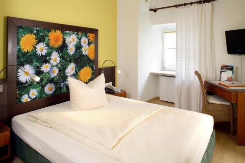 a bedroom with a white bed with a painting on the wall at Hotel Münchner Hof und Blauer Turm in Regensburg