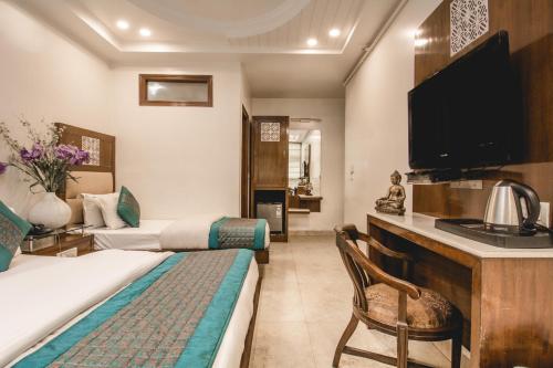 ein Hotelzimmer mit einem Bett und einem TV in der Unterkunft Hotel Sita International in Neu-Delhi