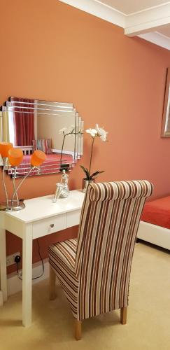 a desk with a chair and a table with a mirror at The Devon Court in Torquay