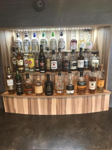 a display of whiskey bottles on a wooden shelf at The Inn @ Y-Not in Thurso