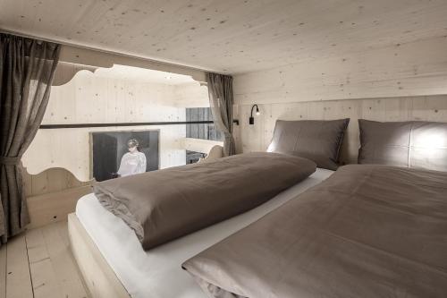 a bedroom with a large bed and a woman in a window at Artefugium Atelier - Apartments in Selva di Val Gardena