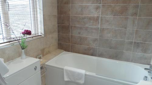 a bathroom with a white tub and a vase with a flower at The Peacock Townhouse Hotel Kenilworth - Warwick in Kenilworth