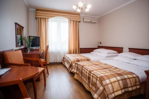 プウォツクにあるPokoje Amore Residenceのベッド2台、テーブル、デスクが備わる客室です。