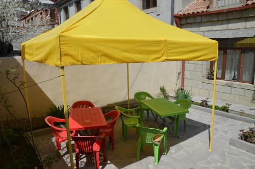 a yellow umbrella with colorful chairs and tables on a patio at Light House Old City in Akhaltsikhe