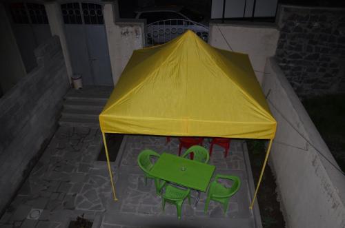 a yellow tent with two green chairs under it at Light House Old City in Akhaltsikhe