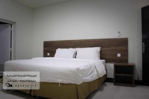 - une chambre avec un grand lit et une tête de lit en bois dans l'établissement المرجانة للشقق المفروشه للعائلات Al Murjana Furnished Apartments for Families, à Al Baha