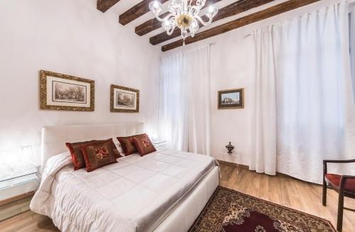 um quarto com uma cama branca e um lustre em CASA DEGLI ANGELI, free wi-fi near San Marco em Veneza