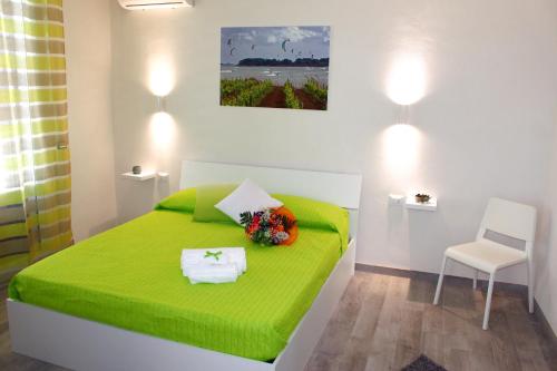 a green bed in a white room with a chair at Sirio Marsala in Birgi Vecchi