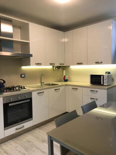 a kitchen with white cabinets and a sink and a table at Lacisivm Lake View in Lazise