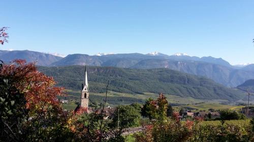 a church steeple in the middle of a valley with mountains at Pension Christl in Caldaro
