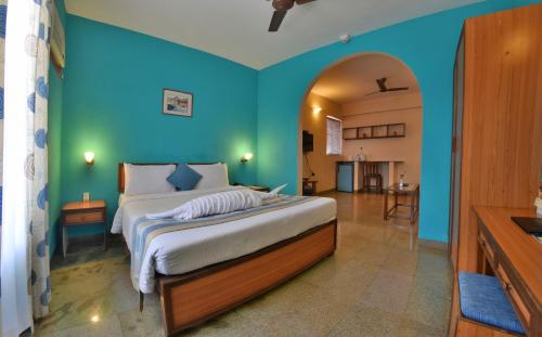 1 dormitorio con 1 cama grande y pared azul en Pride Sun Village Resort & Spa, en Baga